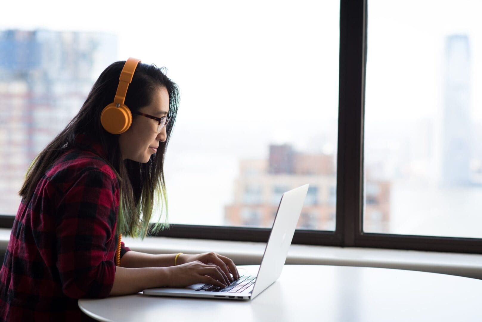 A woman with headphones on looking at her laptop.