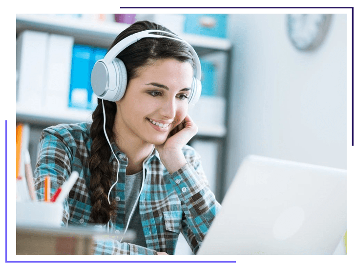 A woman wearing headphones while looking at her laptop.